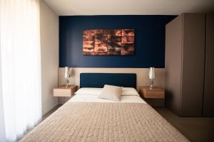 a bedroom with a bed with a blue wall at Maison Selva - Corte Brunati Villetta Deluxe con piscina e garage in Salò +20 photos