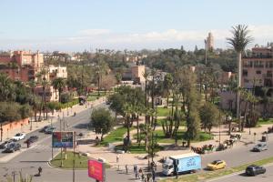 a street in a city with cars and trees at Appartement plein centre marrakech p in Marrakesh