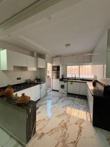 a large kitchen with white cabinets and a marble floor at Appartement plein centre marrakech p in Marrakesh