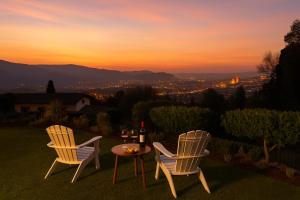 two chairs and a table with a bottle of wine at Panoramic View Village of Villa Luigina Cortona in Castiglion Fiorentino +42 photos