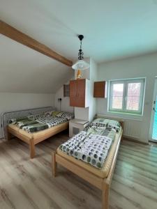 two beds in a room with wooden floors and windows at Chalupa POHÁDKA Moravský kras in Vavřinec