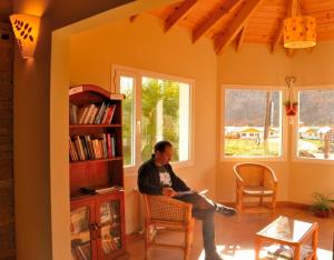 a man sitting on a chair in a living room at Patagonia Hostel in El Chalten