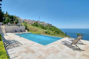 a swimming pool with chairs and the ocean in the background at The View - Apartment with Pool in Blizikuće +16 photos