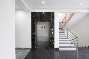 a hallway with stairs and a silver elevator at FabHotel Golden Suites Near Puri Beach in Puri