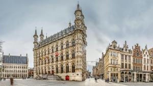 a large building with a clock tower next to other buildings at Allies Avenue in Leuven