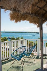 two blue chairs sitting on a balcony overlooking the ocean at Balu Hotel in Isla Mujeres