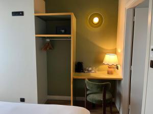 a bedroom with a desk with a lamp and a chair at Monsieur Jules Hôtel Clamart in Clamart +1 photo