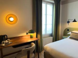a bedroom with a desk and a bed and a window at Monsieur Jules Hôtel Clamart in Clamart