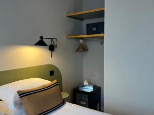 a bedroom with a bed with a green headboard at Monsieur Jules Hôtel Clamart in Clamart