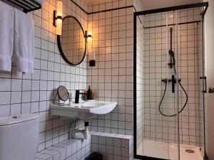 a white tiled bathroom with a sink and a shower at Monsieur Jules Hôtel Clamart in Clamart