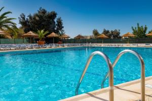 a swimming pool at a resort with chairs and umbrellas at Sea House Apartment - Private Condo with 4 Pools, Jacuzzi & Tennis Court in Albufeira