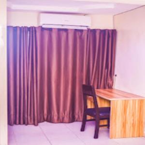 a room with a wooden table and a red curtain at Owee Hotel Apartment and Suites in Lagos