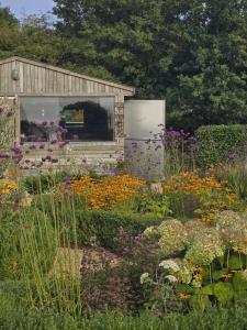 a garden with flowers in front of a shed at The Oaks Glamping - Rubie's Shepherds Hut in Colkirk +6 photos