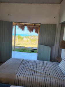 a bedroom with a bed and a large window at Casa Vento e Mar in Japaratinga