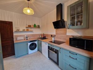 a kitchen with blue cabinets and a washer and dryer at La Chênaie in Crespin +17 photos