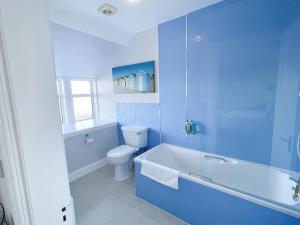 a blue bathroom with a toilet and a bath tub at Cullen Bay Hotel in Cullen