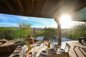 a man standing on the deck of a house with a table at Madikwe Safari Lodge in Madikwe Game Reserve