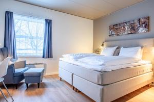 a bedroom with a large white bed and a chair at Højmølle Kro in Eskilstrup
