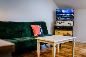 a living room with a green couch and a table at Seenswert - ein Wohlfühlort, in dem ALLE herzlich willkommen sind in Pähl