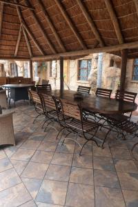a large wooden table and chairs in a room at Ndou The Rocks Lodge in Hammanskraal Station