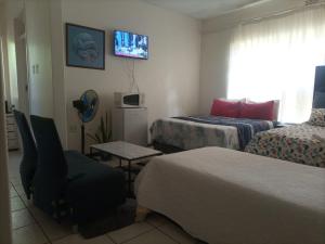 a hotel room with two beds and a chair at Matte Guest House in Potchefstroom