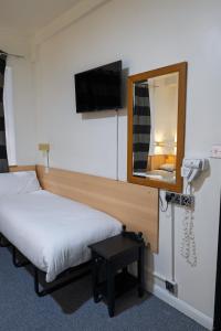a hotel room with a bed and a mirror at St George Hotel Paddington in London