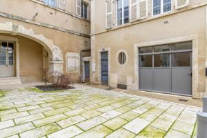 a building with two garage doors and a courtyard at Cour des Moines - centre ville in Le Blanc