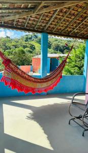 a hammock hanging from a building with a chair at Casarão Vale das Hortênsias in Bonito