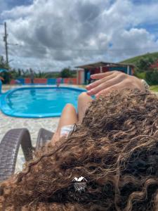 a person laying in a chair with long hair next to a pool at Casarão Vale das Hortênsias in Bonito