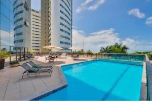 a pool at a hotel with chairs and tables at BEACH CLASS INTERNACIONAL FRENTE MAR in Recife
