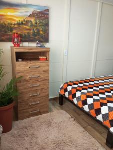 a bedroom with a bed and a dresser and a painting at Cantinho do Sossego in Prudentópolis