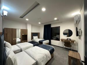 a hotel room with two beds and a desk at MyFlower 1 Hotel in Erbil