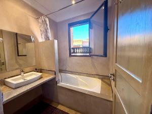 a bathroom with a sink and a tub and a window at Beach Mama Waky Marrakech Appartement Premium Piscine & Vue Atlas in Marrakesh