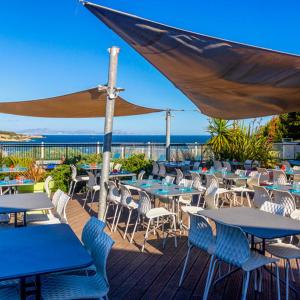 a deck with tables and chairs and an umbrella at Camping l'Arquet - Mobil-home Premium 4 pièces 6 personnes climatisé MAE-3771 in Martigues