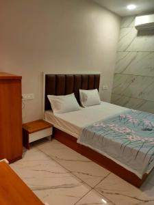 a bedroom with a bed with a wooden headboard at HOTEL JANTA INn in Vapi