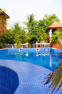 a large blue swimming pool with trees in the background at Frenezia Hotel and Apartment Ikeja GRA in Ikeja