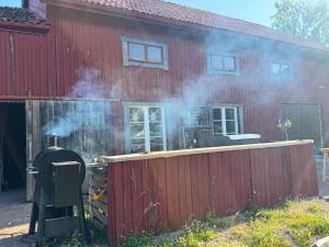 een huis waar rook uitkomt, naast een hek bij Muntergården i Nusnäs in Nusnäs