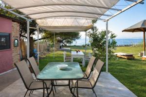 a patio with a table and chairs under a pergola at Beachfront Bliss in Corfu - Vasiliki's Sea House in Lefkimmi