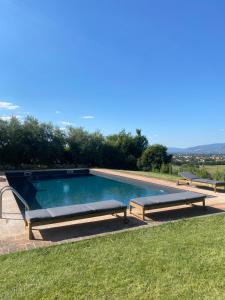 a swimming pool with two benches in the grass at Luxury Villa Spoleto in Spoleto