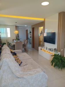 a living room with a couch and a tv at Quarto próx a Praia do Morro in Guarapari
