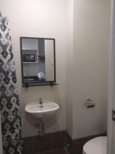 a bathroom with a sink and a mirror and a toilet at MetroStay Studio Legarda in Manila
