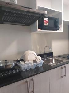 a kitchen counter with dishes and a sink and a sink at MetroStay Studio Legarda in Manila