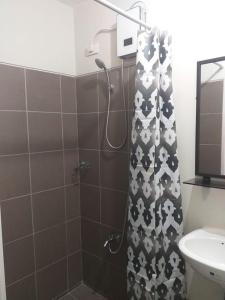 a bathroom with a shower with a black and white shower curtain at MetroStay Studio Legarda in Manila