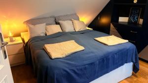 a blue bed with two pillows on top of it at Castello Rosso Apartman in Pilisvörösvár