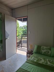 a bedroom with a green bed and a balcony at Nancy's Place in Caniton