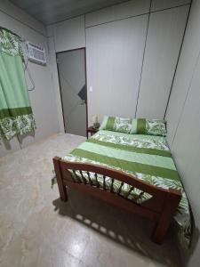 a small bedroom with a bed with green sheets at Nancy's Place in Caniton