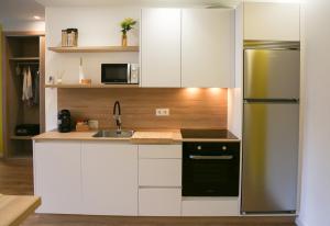 a kitchen with white cabinets and a stainless steel refrigerator at Apartamento Mimosa Diseño Exclusivo in Ponteareas