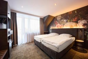 a bedroom with a bed with a painting on the wall at Hotel Elsen in Grevenbroich