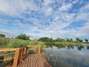 a wooden dock on a lake under a cloudy sky at Domki nad Szóstakiem in Orzechowo