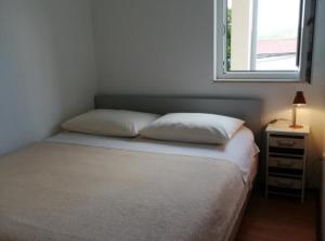 a bed with two pillows and a window in a room at Sanja Apartments Posedarje in Posedarje